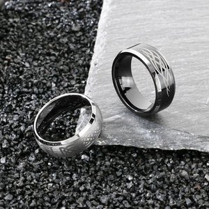 Detail of silver and black tungsten rings with celtic knot flame pattern on rocky surface