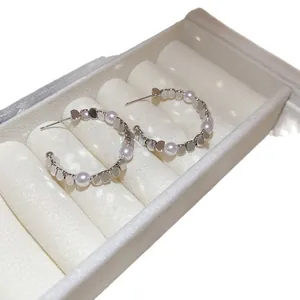 Elegant silver needle pearl hoop earrings with polished metal accents in a jewelry box