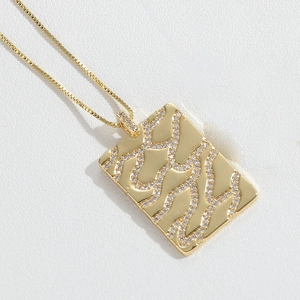 Macro shot of gold rectangle pendant with wavy texture and micro-pave zircons