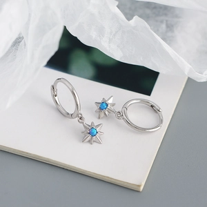 Macro view of silver star earrings with blue opal stone and polished geometric finish