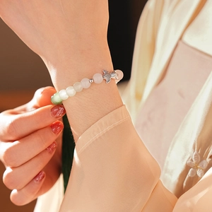 Detail of beaded chalcedony bracelet with fish pendant on model's wrist