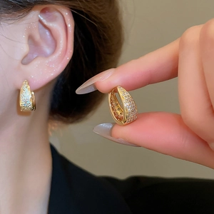 Detail of gold U-shaped hoop earrings with micro-pave cubic zirconia on a model
