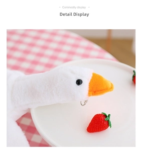 Detail of soft white plush goose bag featuring orange beak and metal ring accessory