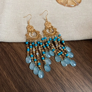 Close-up of bohemian tassel earrings with blue beads and water-drop pendants