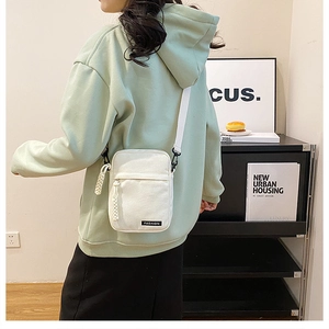 White canvas mini crossbody bag worn by model in a minimalist lifestyle setting
