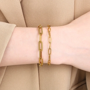Detail von geschichteten Goldkettenarmbändern mit Magnetverschluss an einem Ärmel