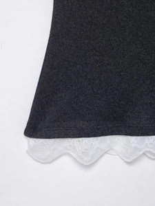 Détail du haut en tricot gris chiné avec bordure en dentelle blanche sur l'ourlet