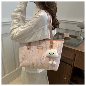 Close-up of pink tote bag featuring multi-colored wavy embroidery and cloud plush charm