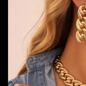 Close-up of golden chunky chain necklace and matching earrings set on a model