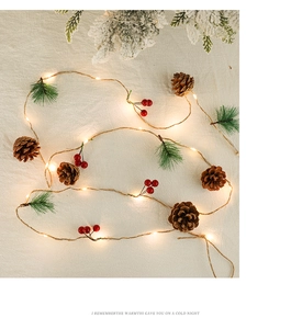 Close-up of LED Christmas fairy lights with pine cones, red berries and green needles