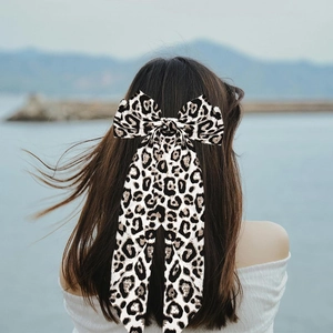 Detail of elegant leopard print bow hair clip with long ribbons on a model back