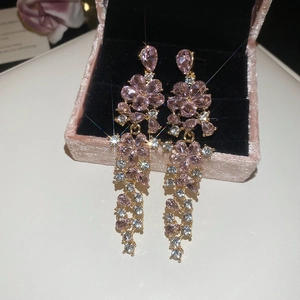 Detailed view of gold flower tassel earrings with pink crystals in a velvet jewelry box