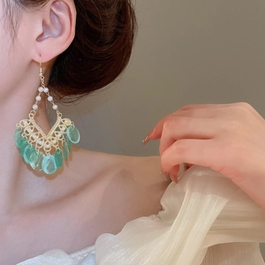 Detail of bohemian gold wire tassel earrings with white pearls and green drop pendants