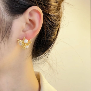 Elegant gold flower pearl stud earrings for women shown on a model side profile
