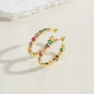 Detail shot of 14K gold-plated hoop earrings with multi-colored zircons on white stone