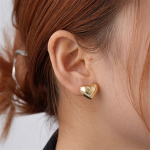 Minimalist gold heart-shaped stud earrings with polished finish and grooved texture