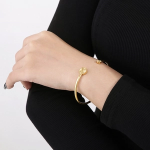 Close-up of golden stainless steel C-shaped cuff bracelet with sunburst texture detail