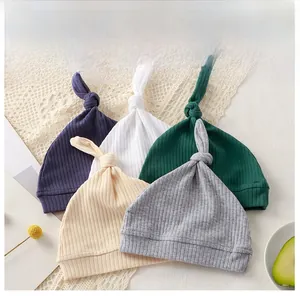 Flat lay of five newborn ribbed knit knotted hats in navy, white, green, beige, and grey