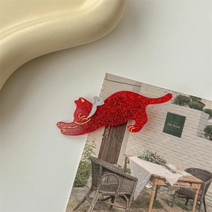Close-up of red glitter cat-shaped hair clip with gold details and silver wing accent