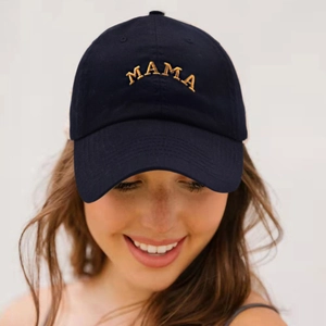 Close-up of navy cotton baseball cap featuring golden MAMA embroidery on a model
