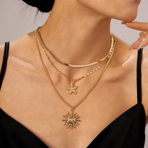 Detailed layered necklace set with golden sun face and starfish charms on a model