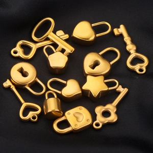 Golden heart lock and vintage key pendants displayed on a lustrous dark fabric