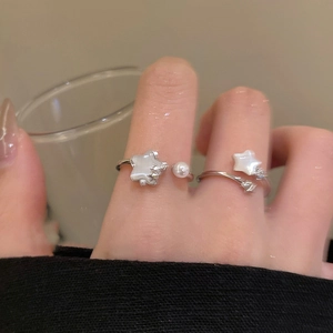 Detail view of silver open rings with star motifs and pearls worn on fingers