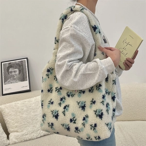 Detailed plush tote bag with blue flower pattern and branding label in lifestyle setting