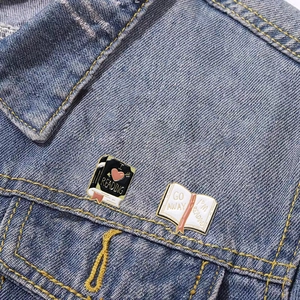 Cartoon enamel book brooches with I Love Reading text on a blue denim jacket collar