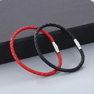 Détail de bracelets tressés en cuir rouge et noir avec fermoirs magnétiques en argent