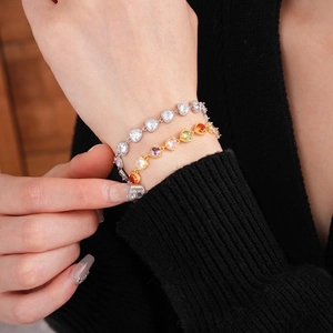 Elegant gold and silver heart bracelets with colorful zircon stones on woman's wrist