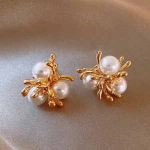 Detailed view of elegant gold pearl earrings on luxurious gold silk background texture