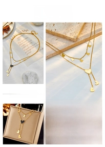 Detail view of double-layer gold titanium steel necklace with black enamel heart pendant