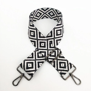 Detail of black and white geometric diamond weave bag strap with dark metal hardware