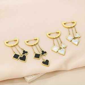 Detail of tassel earrings featuring clover and heart pendants in gold with black and white finish