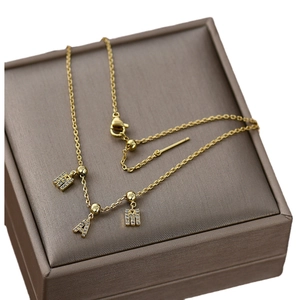 Golden chain necklace with sparkling A and H zircon pendants in a brown display box