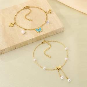 Gold butterfly anklet with pearl fringe, cactus and cherry charms on a stone background