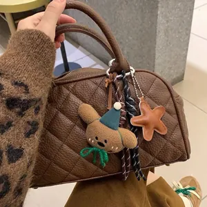 Dettaglio borsa in pelle trapuntata marrone con ciondolo a forma di orso e di stella