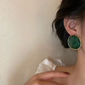 Elegant round green marble earrings with gold trim worn by a model in soft light