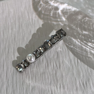 Detailed view of silver hair clip with gray square crystals and white round pearl
