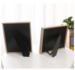 Detail of wooden picture frame back with sturdy stand and metal clips on white table