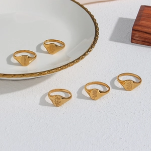 Close-up of five gold stainless steel signet rings with engraved floral patterns