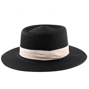 Macro shot of black straw hat weaving texture and cream-colored fabric ribbon detail