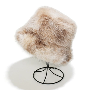 Detail of plush faux mink bucket hat in beige showing fluffy texture on a metal stand