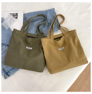 Detail view of canvas tote bags in olive green and mustard yellow with fashion label