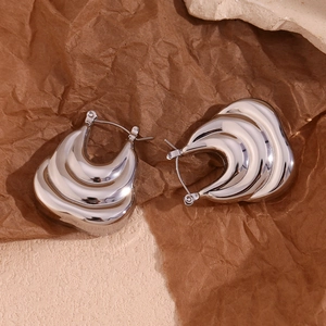Detailed view of silver thick wave-textured earrings with fluid hollow layered design