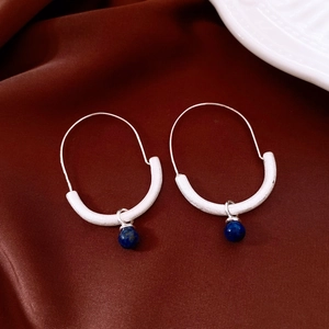 Detailed close-up of matte silver hoop earrings with round blue tiger eye pendants