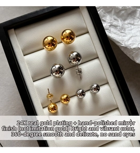 Macro view of minimalist gold and silver ball stud earrings in various sizes on a tray