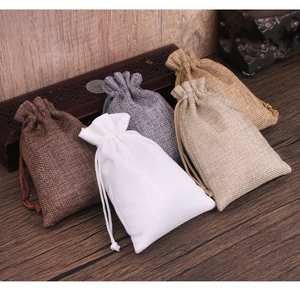 Macro detail of multicolored linen drawstring pouches on a rustic dark wood background