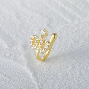 Macro shot of gold crown nose cuff featuring white cubic zirconia on stone background